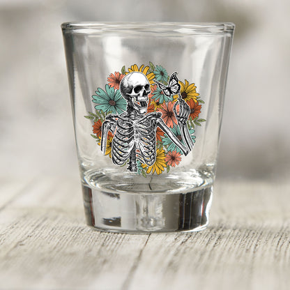 Skeleton Floral shot glass UV DTF transfer with skeleton with wildflowers and a butterfly on a clear shot glass