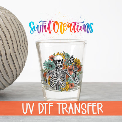 Skeleton Floral UV DTF transfer on a clear shot glass with the Swiit Creations logo and UV DTF Transfer banner