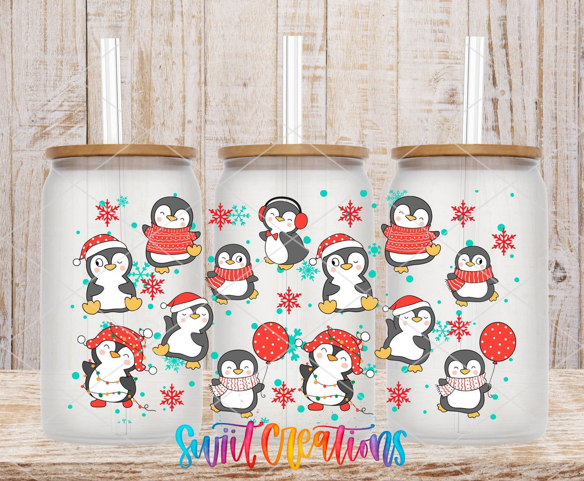 Christmas Penguins UV DTF wrap on three clear glass cans with bamboo lids