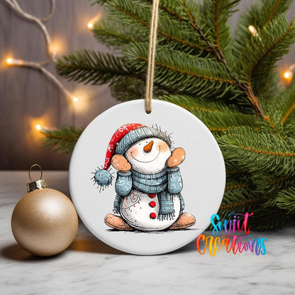 Sitting Snowman in Santa Hat ornament UV DTF transfer on a hanging ornament with pine branches and a gold bauble