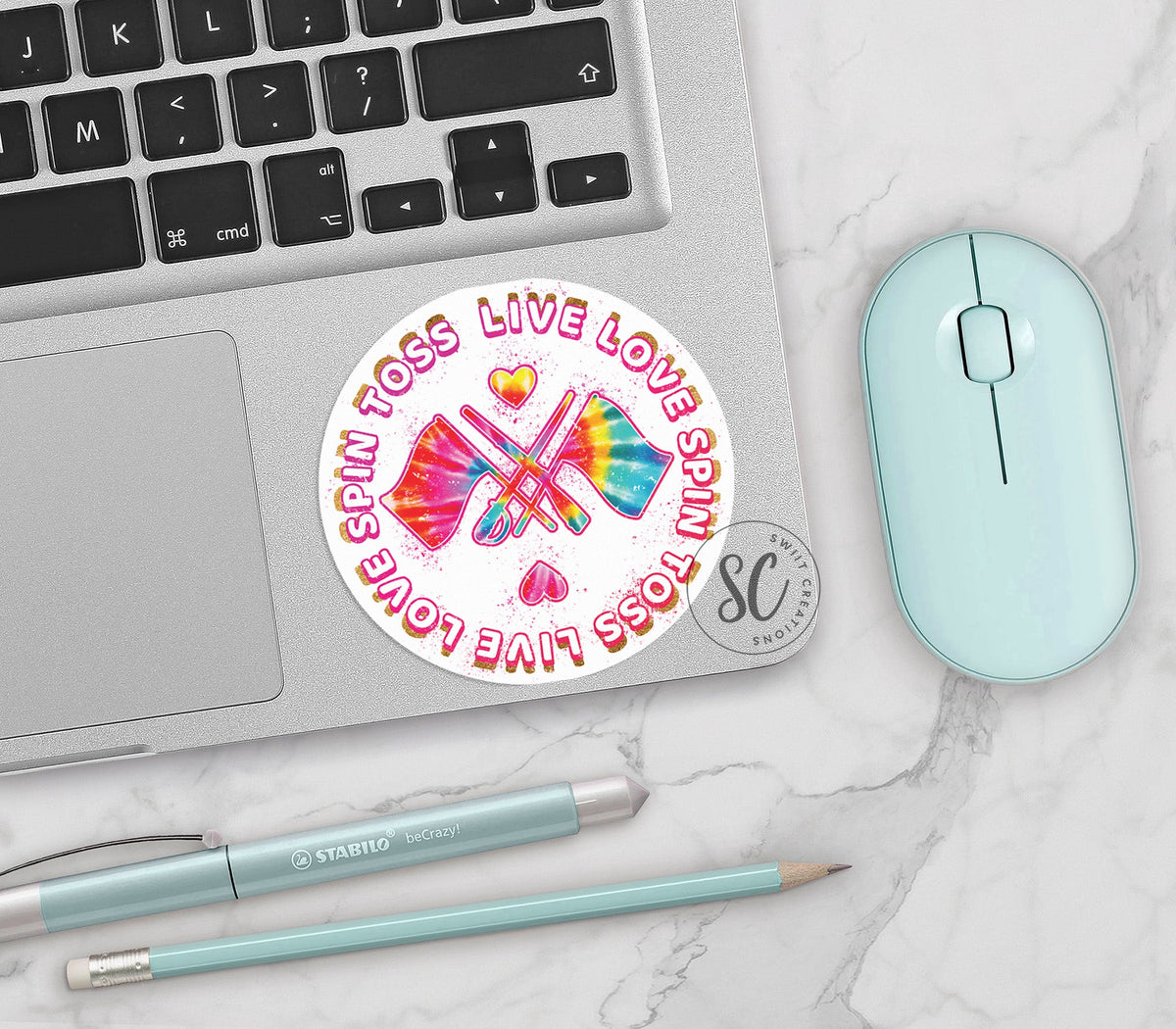 Spin Toss Live Love vinyl sticker on a silver laptop next to a mint mouse and pens