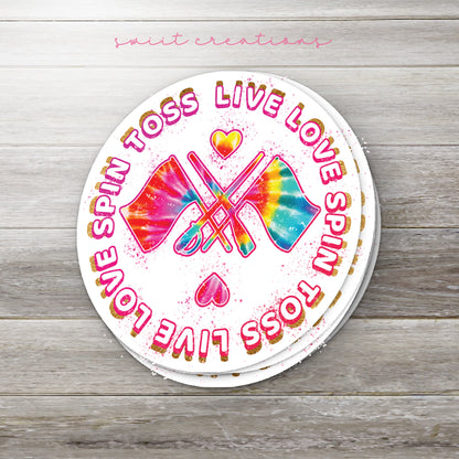 Stack of Spin Toss Live Love glossy stickers on a gray wood table