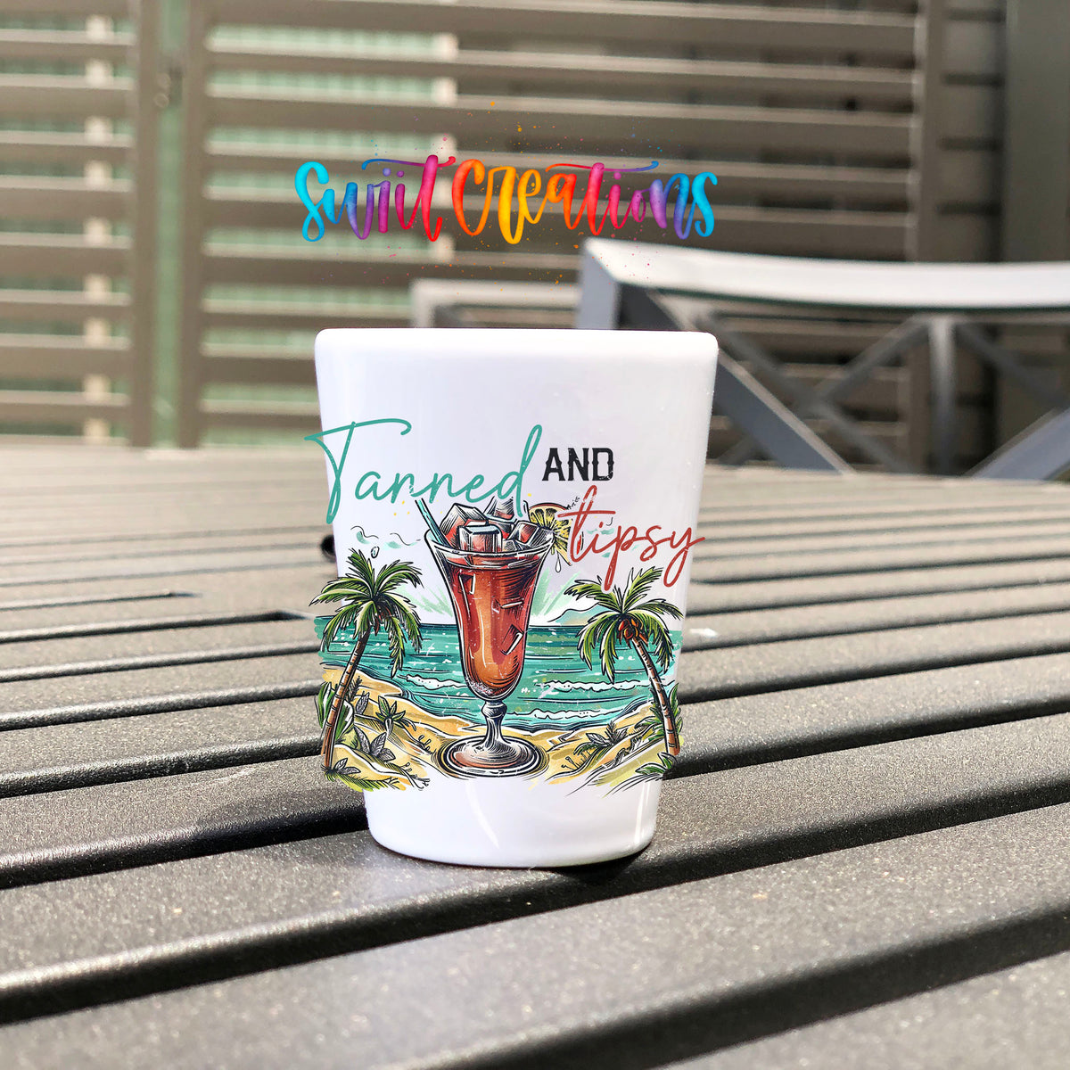 Tanned and Tipsy UV DTF transfer on a white shot glass on an outdoor patio table