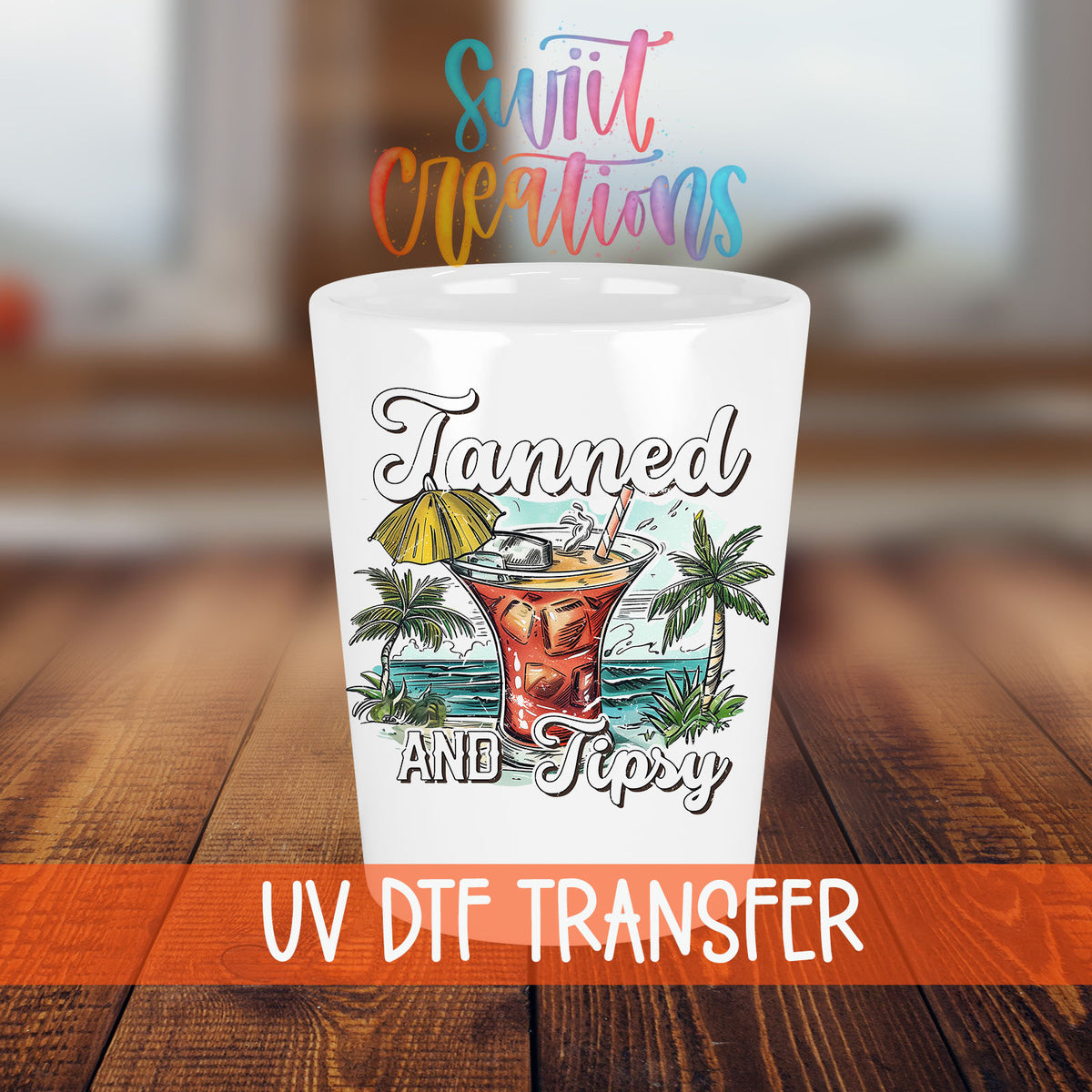 Tanned and Tipsy shot glass transfer on a white shot glass on a wooden table