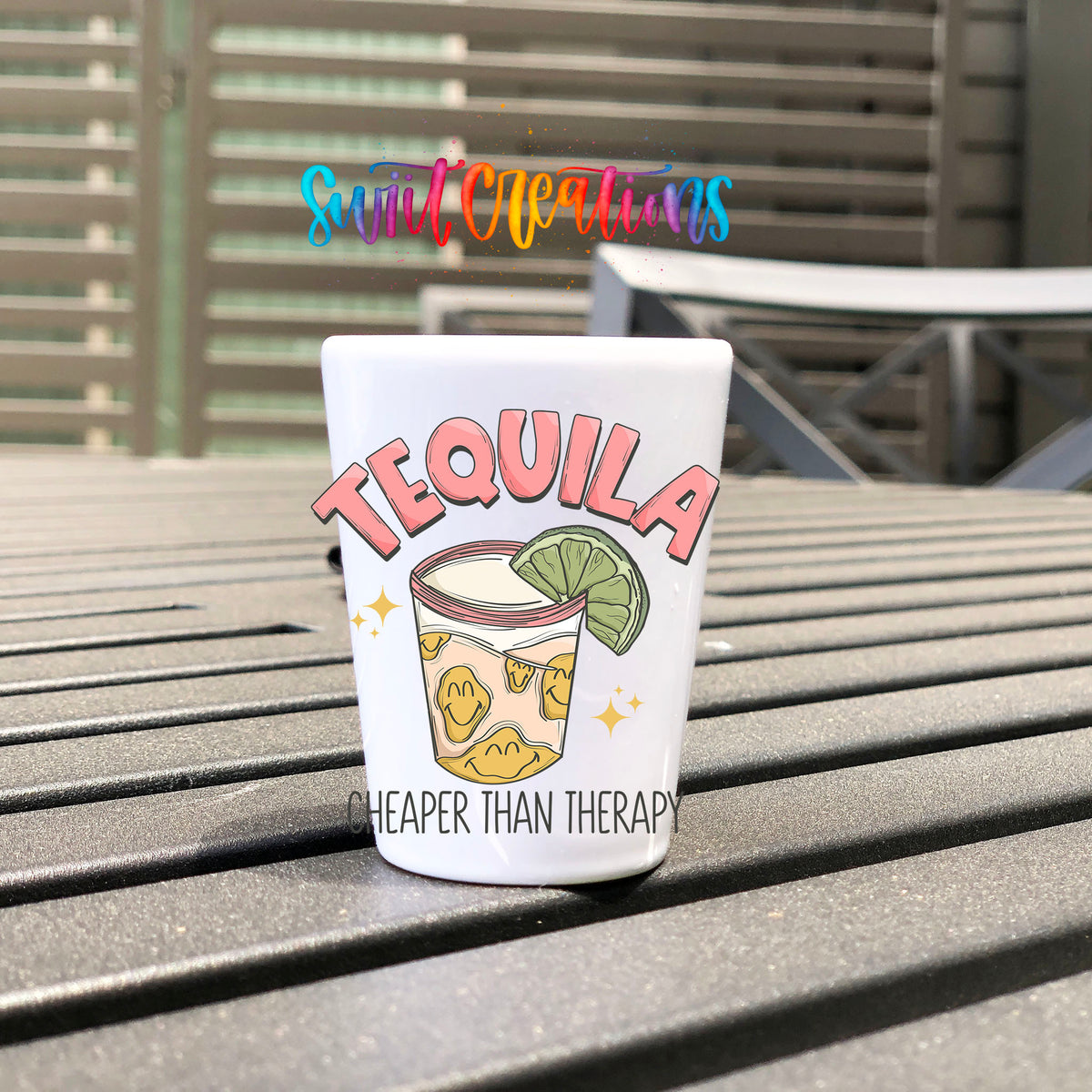 Tequila Cheaper Than Therapy UV DTF transfer on a white shot glass on an outdoor patio table