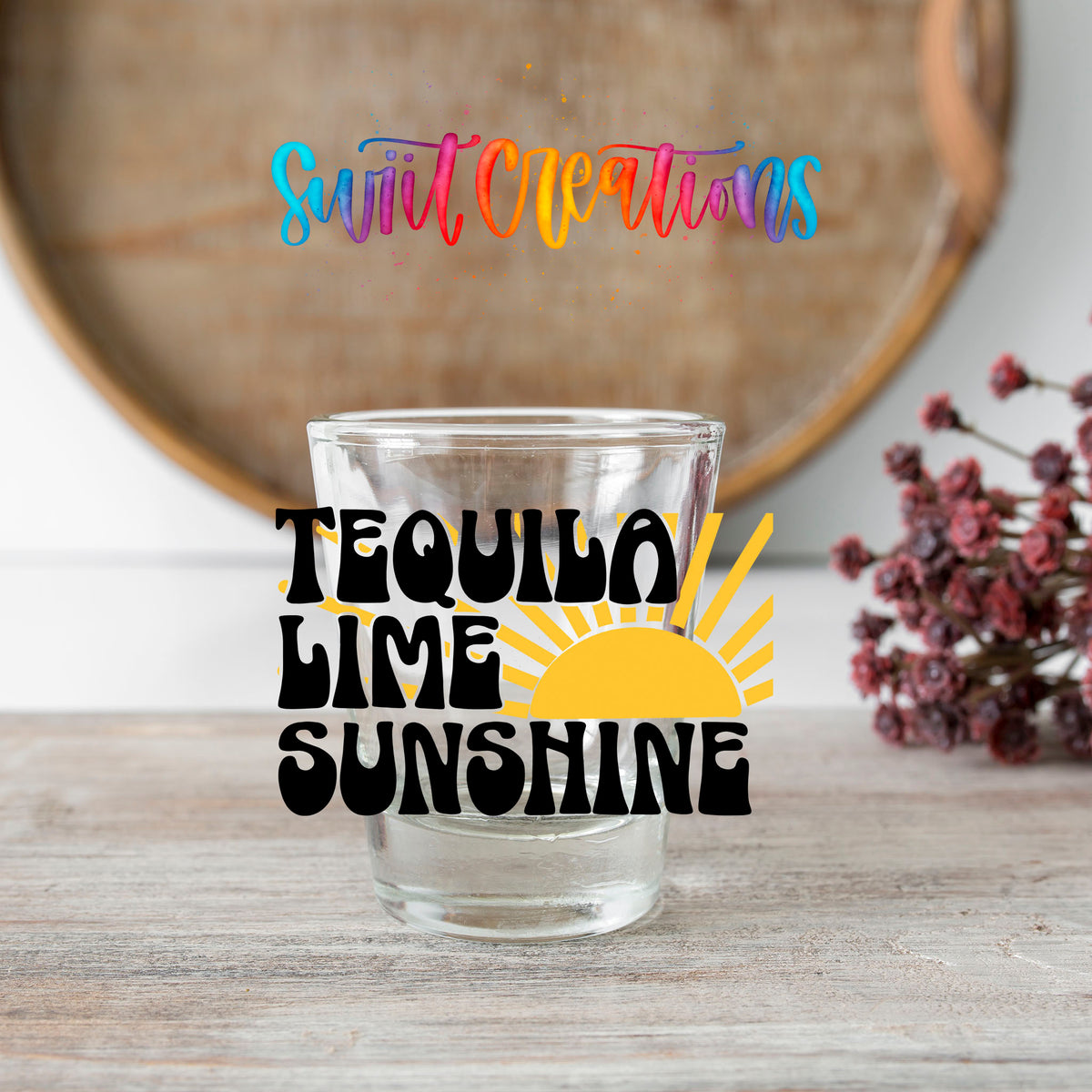 Tequila Lime Sunshine shot glass transfer on a clear glass beside a wooden barrel and dried flowers