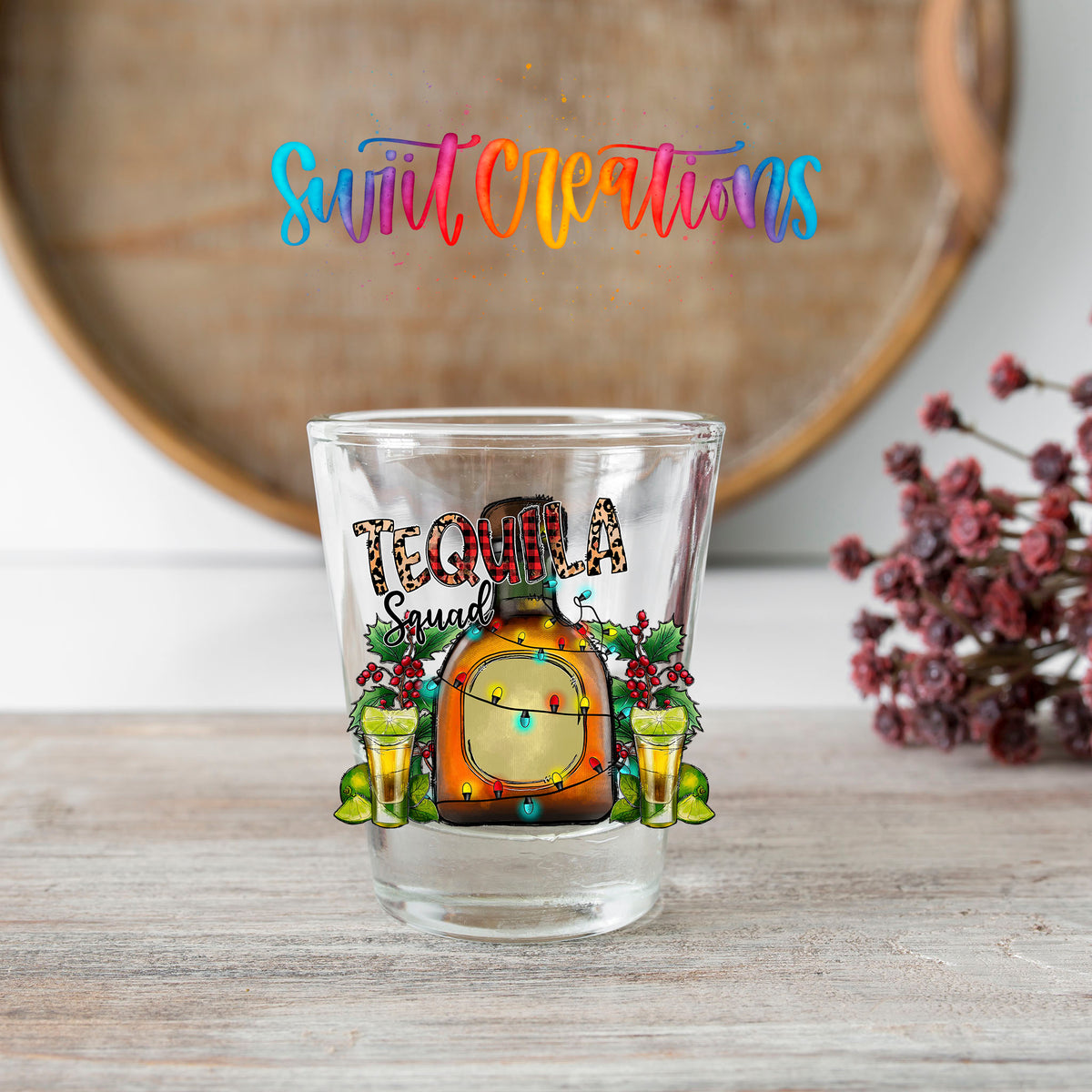 Tequila Squad shot glass transfer on a clear glass beside a wooden barrel and dried flowers