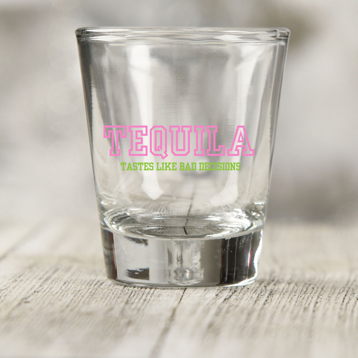 Tequila Tastes Like Bad Decisions shot glass UV DTF transfer with pink varsity-style lettering on a clear shot glass