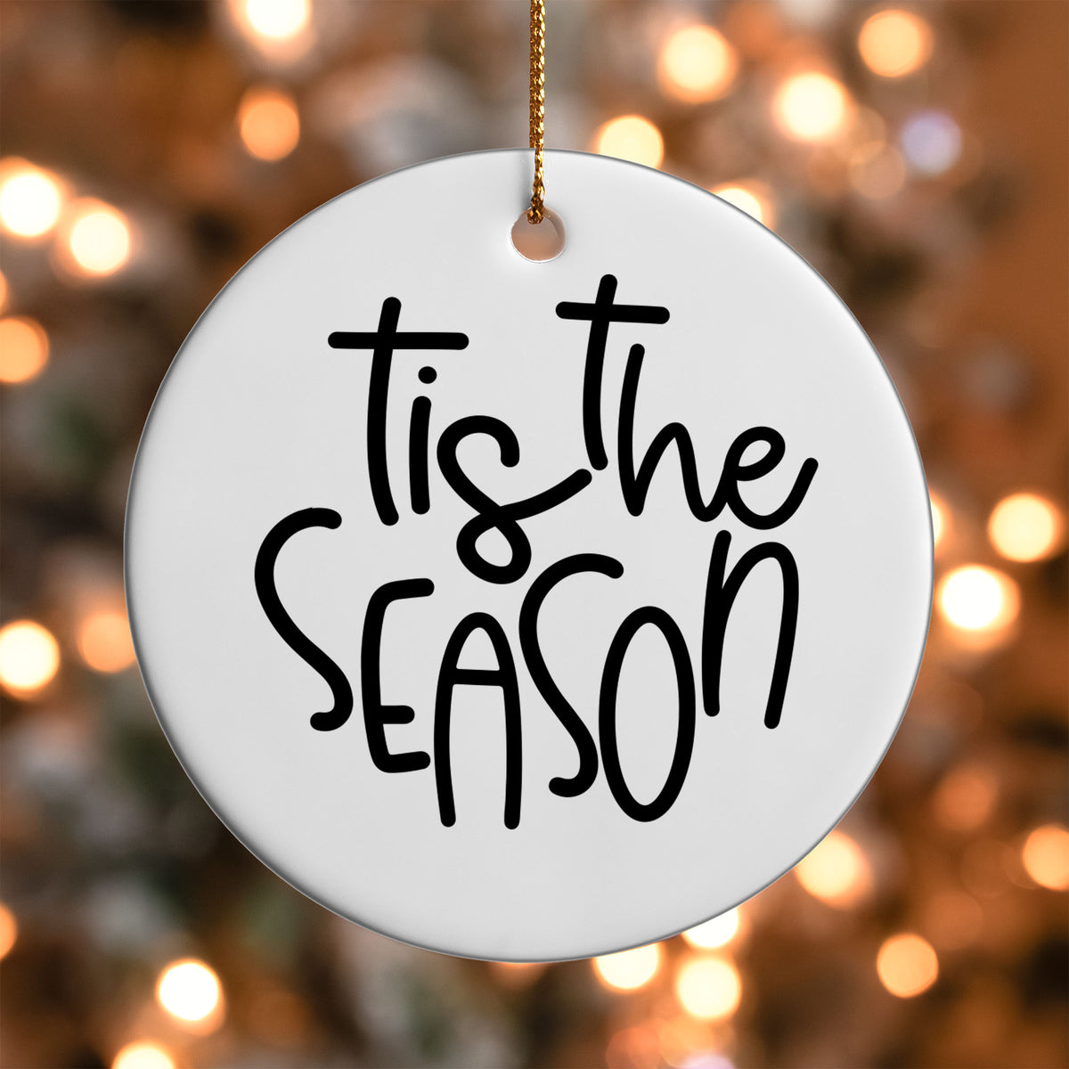 Tis the Season ornament UV DTF transfer on a round white ornament with a bokeh light background