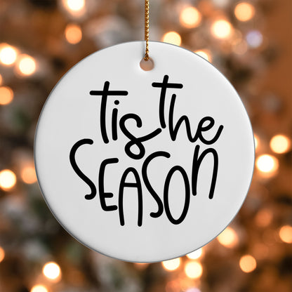 Tis the Season ornament UV DTF transfer on a round white ornament with a bokeh light background