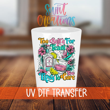 Too Salty For Tears Too Tipsy To Care shot glass transfer on a white shot glass on a wooden table