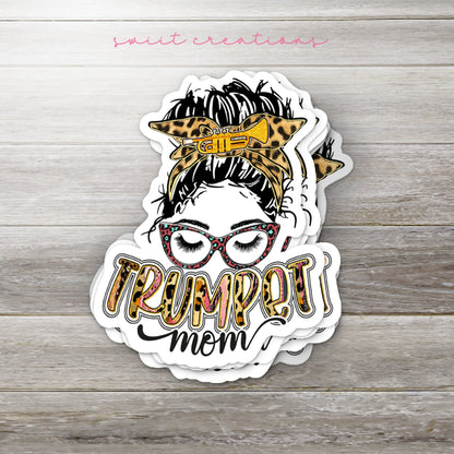 Stack of Trumpet Mom glossy stickers on a gray wood table