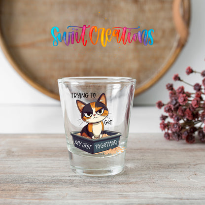 Trying to Get My Sh*t Together shot glass transfer on a clear glass beside a wooden barrel and dried flowers