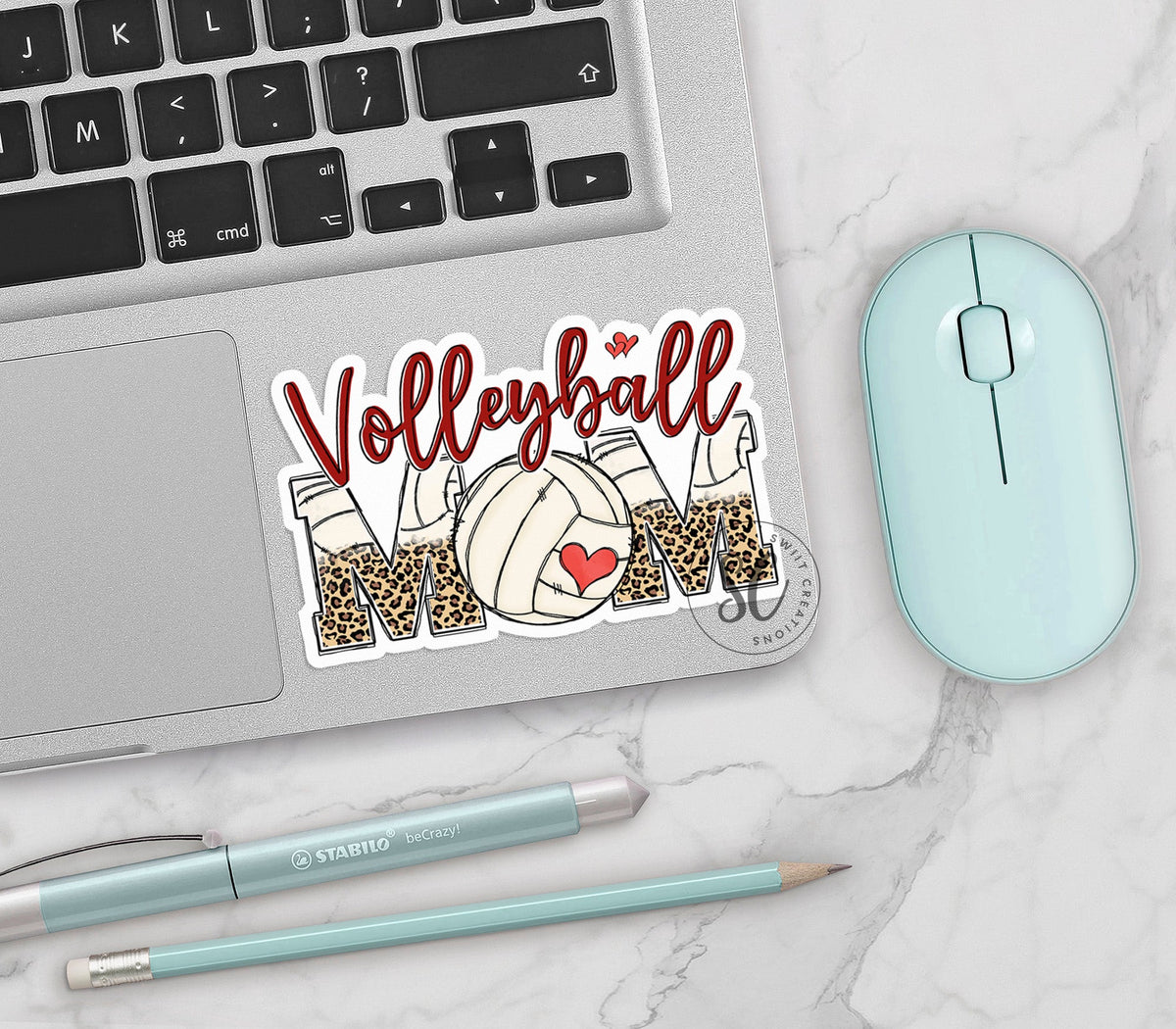 Volleyball Mom vinyl sticker on a silver laptop next to a mint mouse and pens