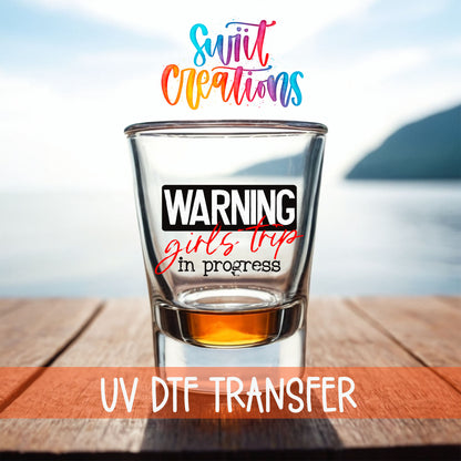 Warning Girls Trip in Progress shot glass UV DTF transfer on a filled shot glass on a dock by the water