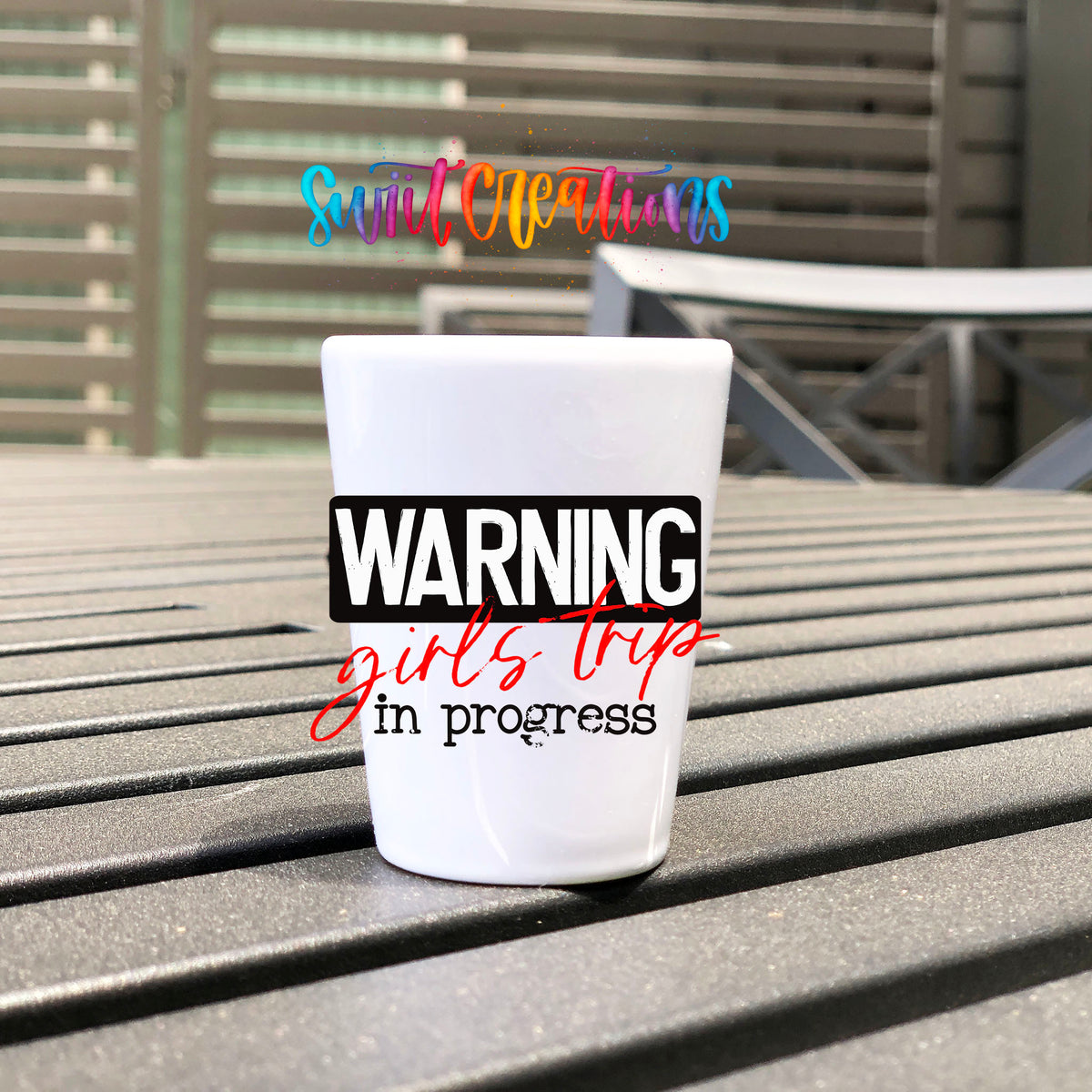 Warning Girls Trip in Progress UV DTF transfer on a white shot glass on an outdoor patio table