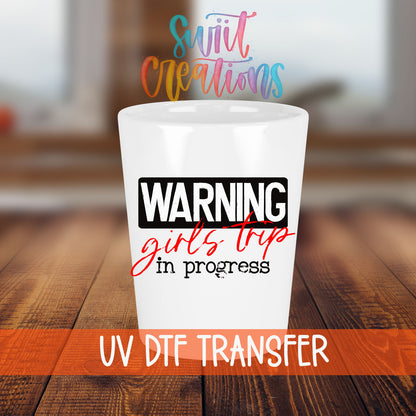 Warning Girls Trip in Progress shot glass transfer on a white shot glass on a wooden table