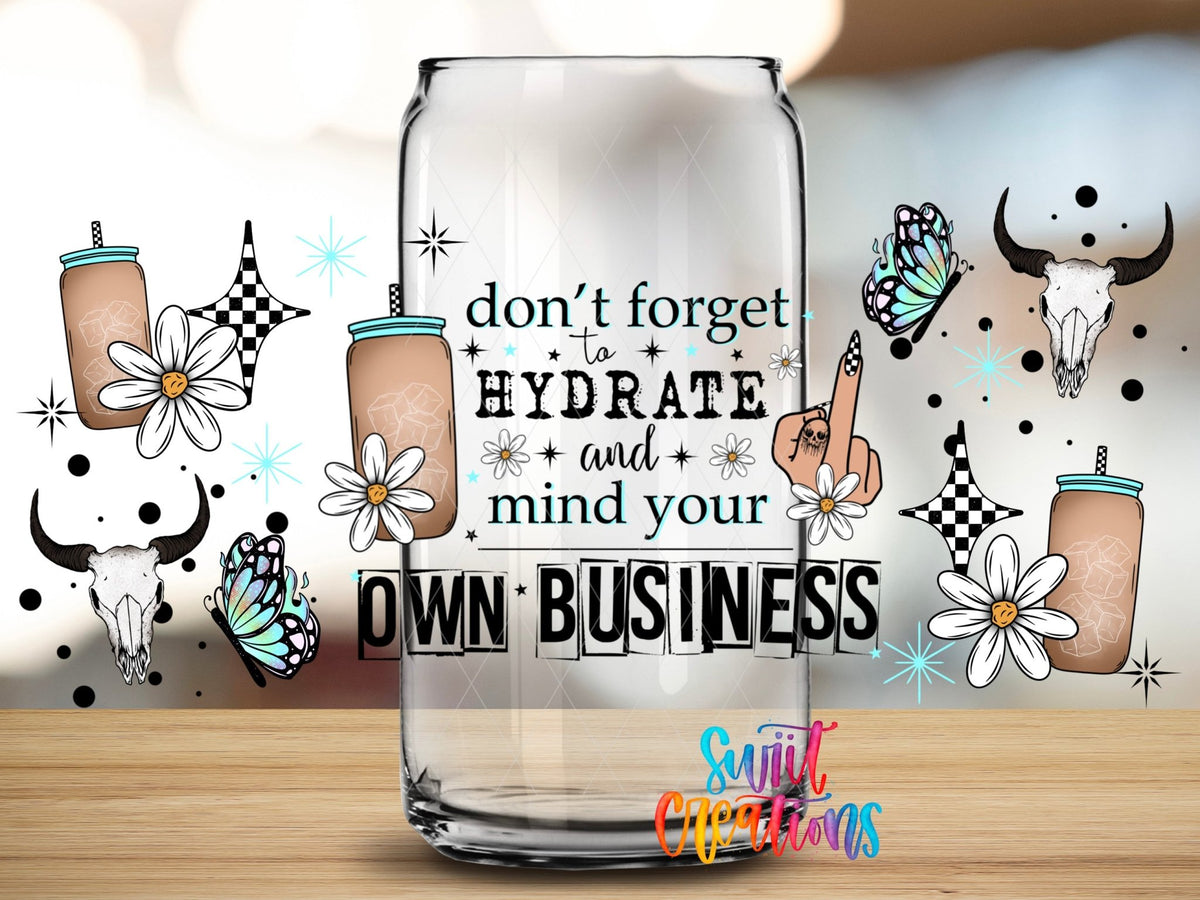 Close-up of the Don't Forget to Hydrate and Mind Your Own Business UV DTF wrap on a clear glass can
