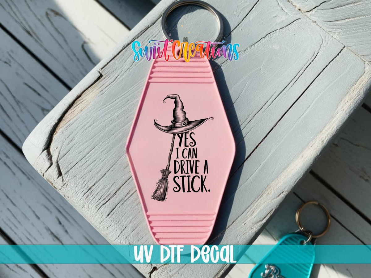 Yes I Can Drive a Stick UV DTF transfer on a pink motel keychain on a wood board