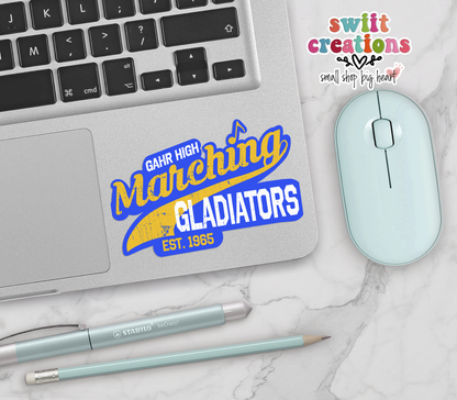 Gahr High Marching Gladiators vinyl sticker on a silver laptop next to a mint mouse and pens